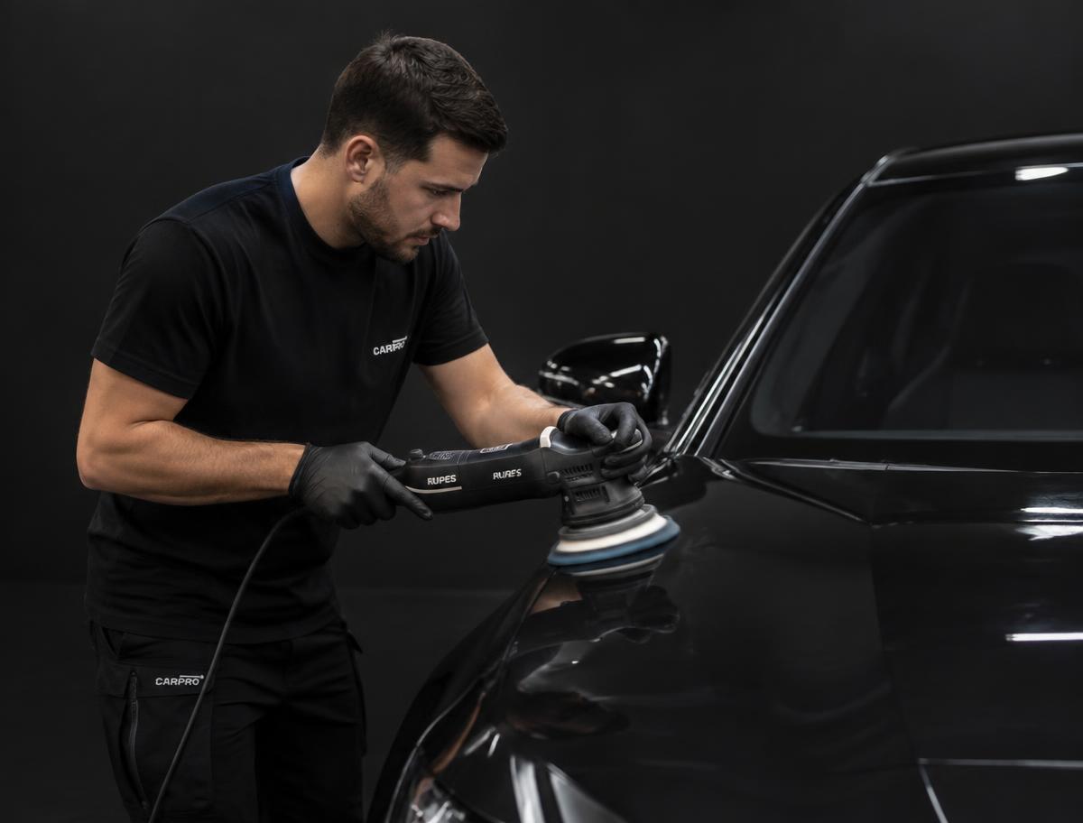 Detailer polijst de lak van een donkere auto